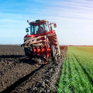 Tractor agricultural machine cultivating field.